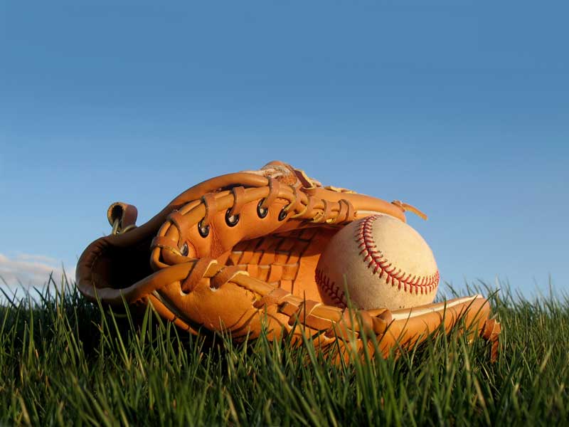 | Bomb Squad Elite baseball mitt and ball on grass under blue sky